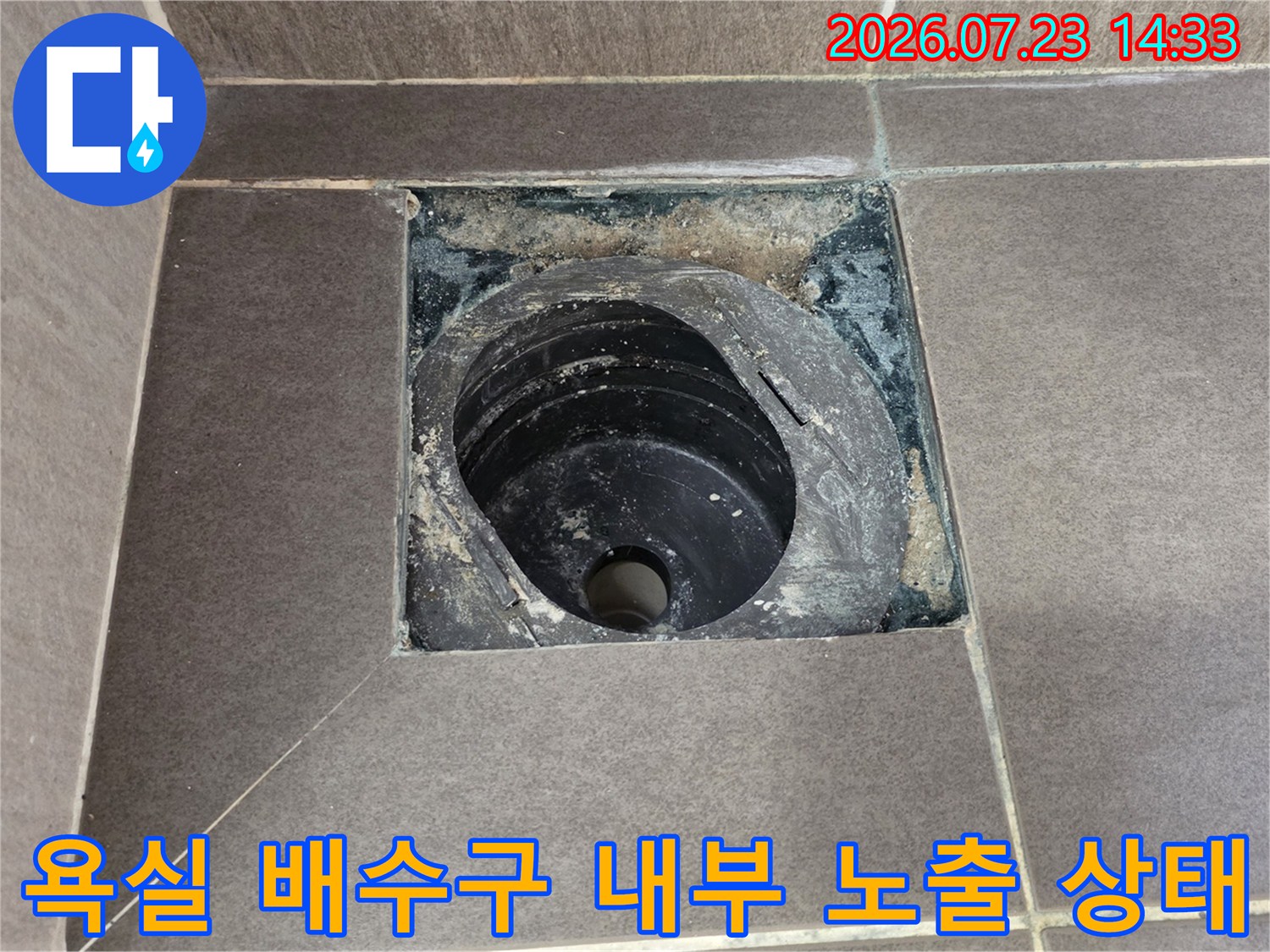 화장실 바닥 타일 사이에 설치된 검은색 플라스틱 배수관-유가 주변의 오염물질과 틈새 모습
