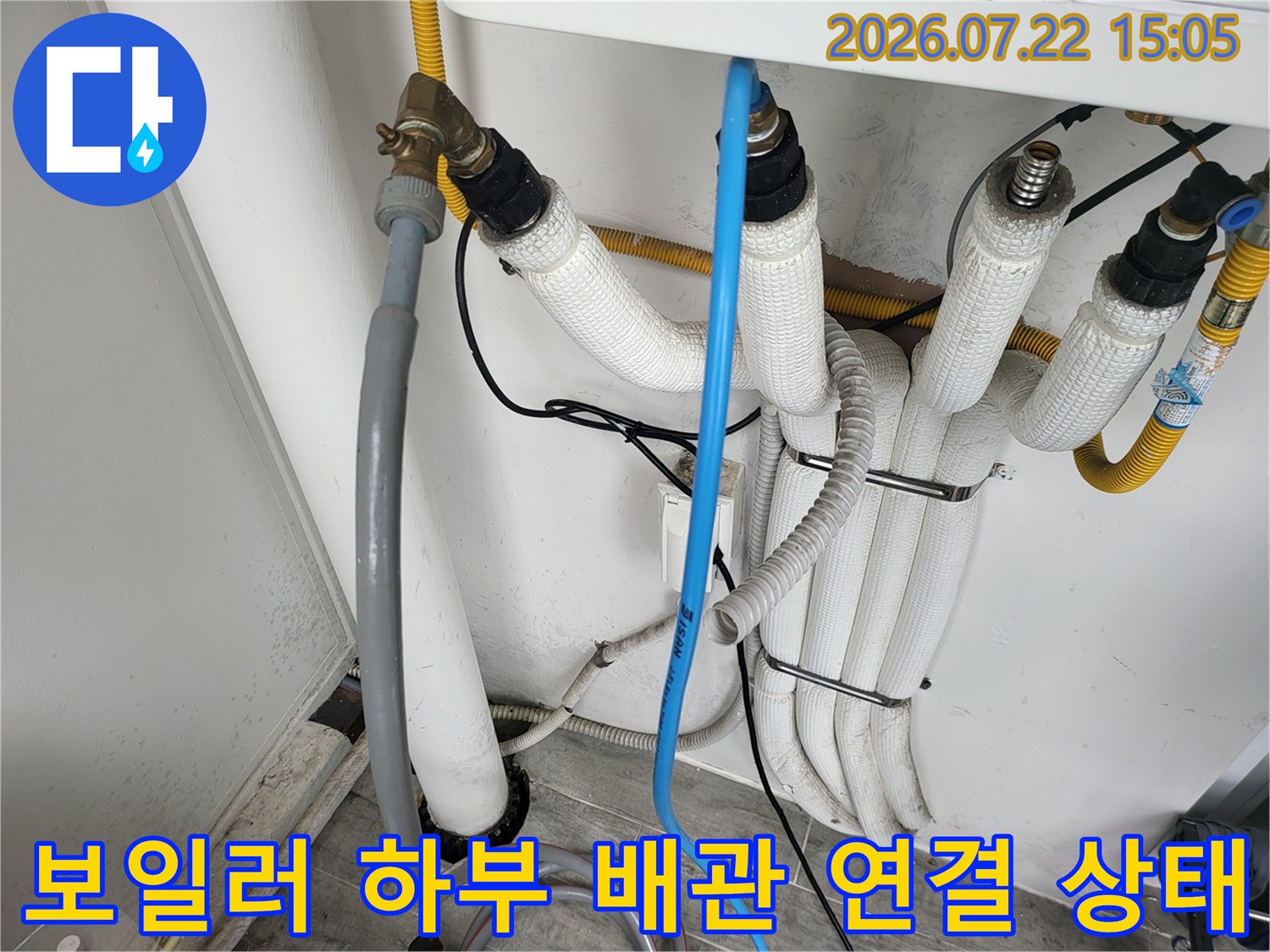 여러 갈래의 흰색 보온재 배관이 묶여 있고 파란색 호스가 세로로 내려오는 모습