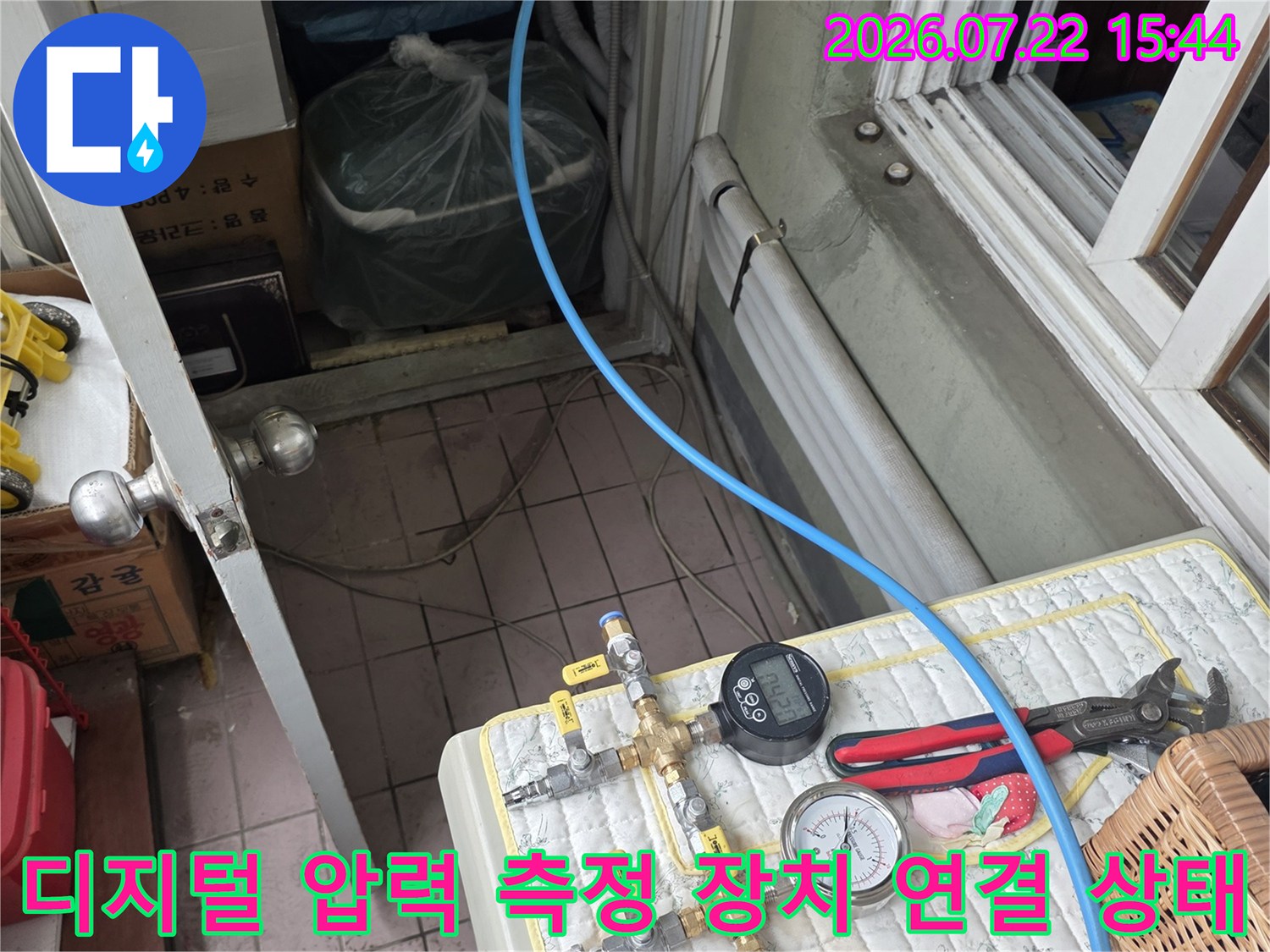 파란색 배관 호스가 디지털-아날로그 게이지에 연결되어 수치를 나타내는 모습