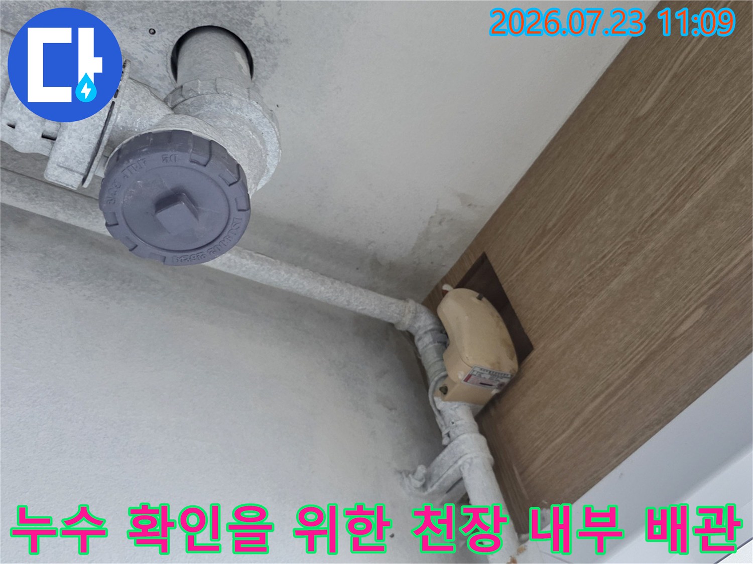 회색의 플라스틱 배관이 지나가는 천장 내부 모습과 점검구 마감재 사진