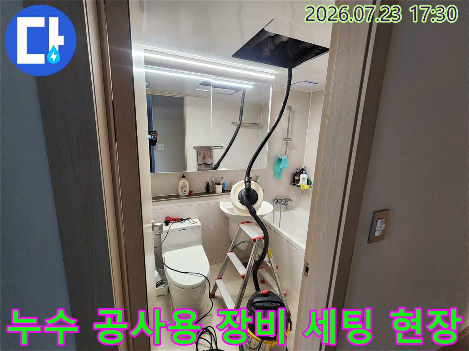 욕실 내부에 설치된-검은색 흡입 호스가 연결된 집진기와 알루미늄 사다리