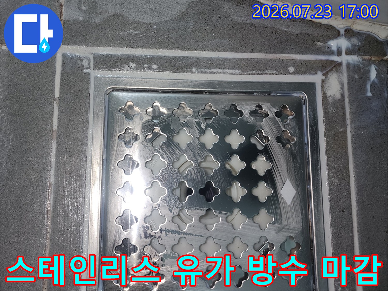 은색의 격자무늬 배수구 덮개가 설치되어 있고 가장자리에 백색 방수 처리가 된 사진