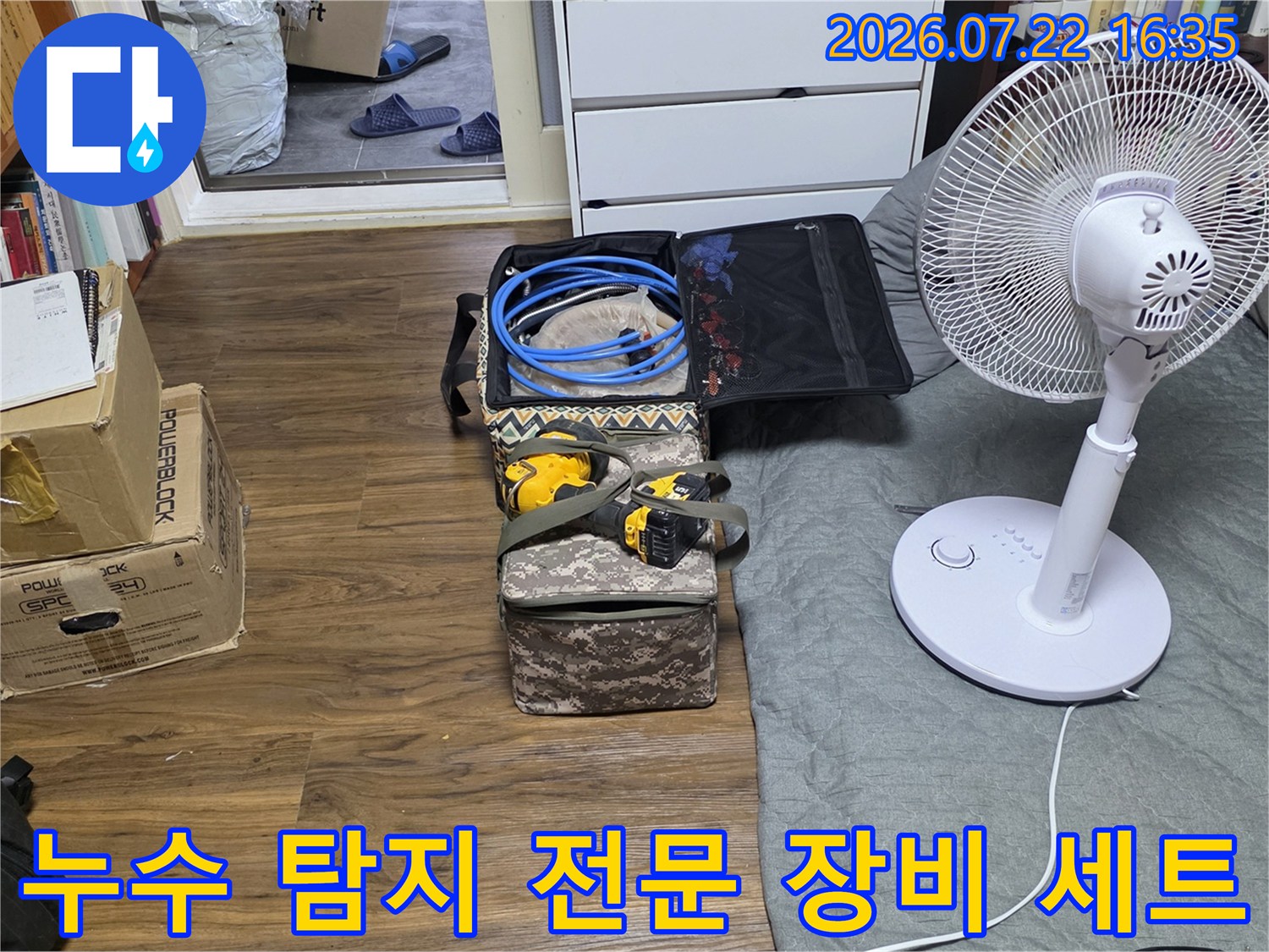 방바닥에 놓인 파란색 호스와 전동공구가 담긴 누수 탐지용 공구함-세트