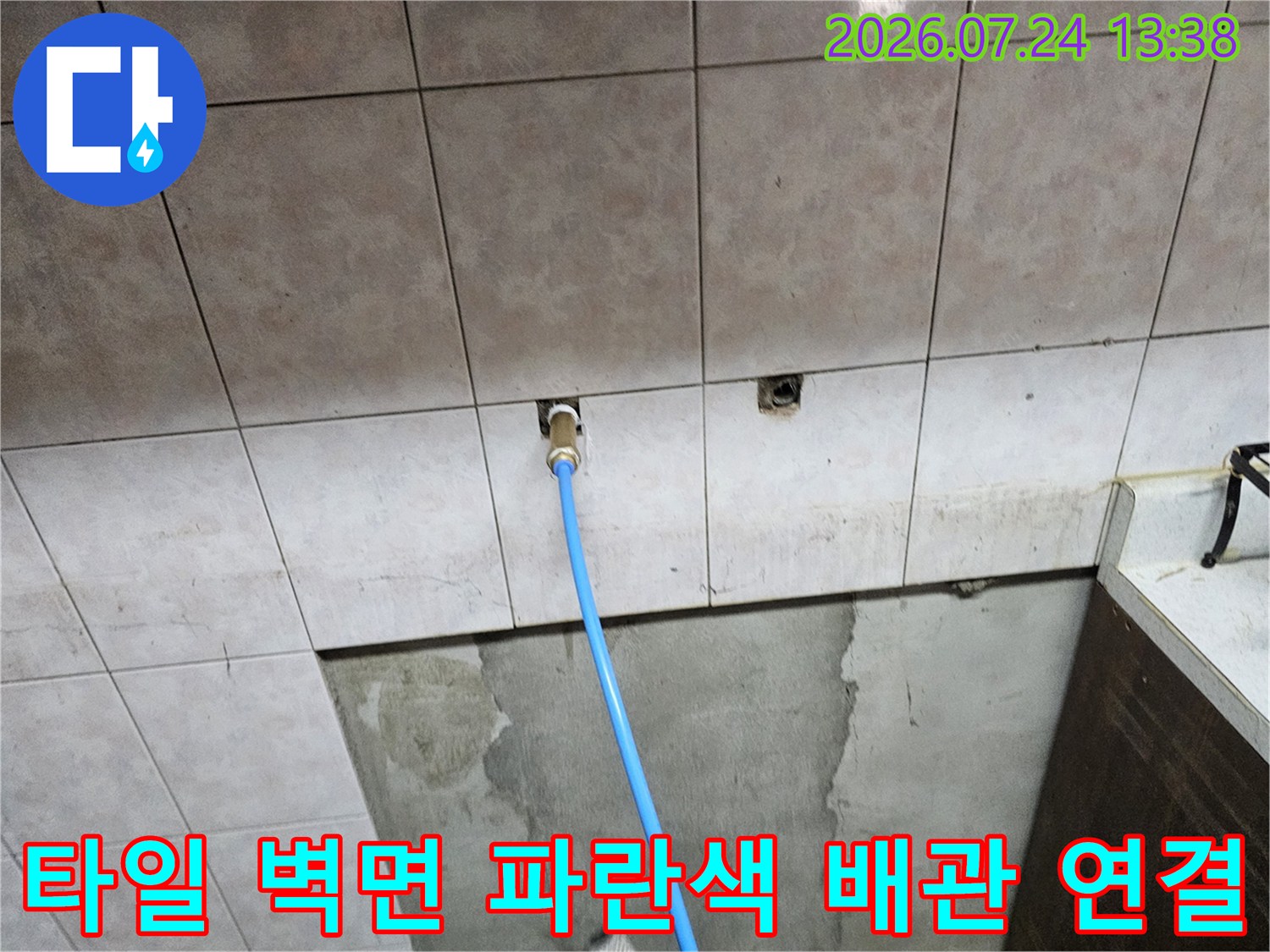 벽 타일 사이로 파란색 보수용 배관이 나와 있는 누수 점검 현장 사진