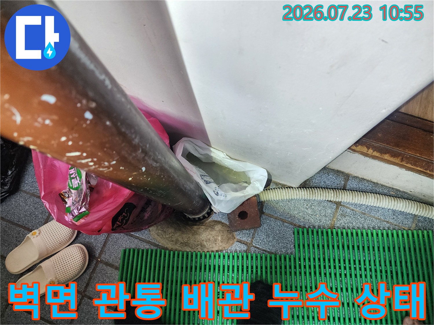 금속 재질의 온수 배관이 하얀색 벽체를 통과하며 바닥으로 연결된 부위의 누수 모습