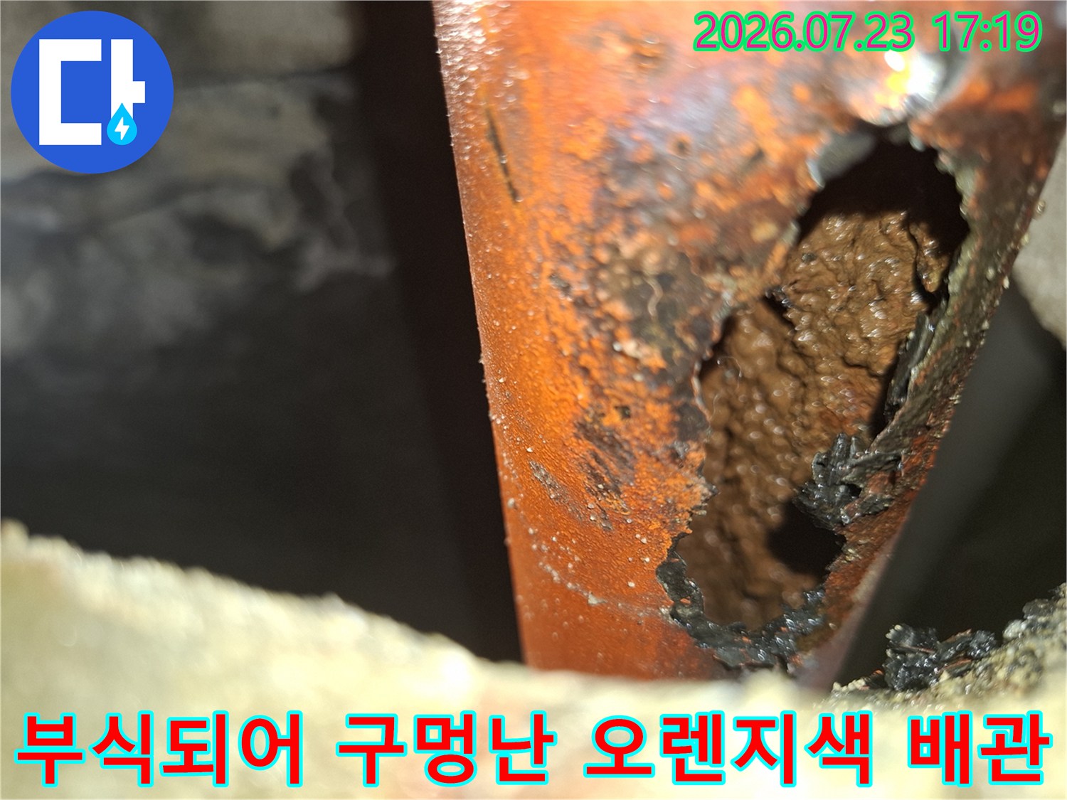 심하게 부식되어 외벽에 커다란 구멍이 뚫린-오렌지색 플라스틱 배관 모습