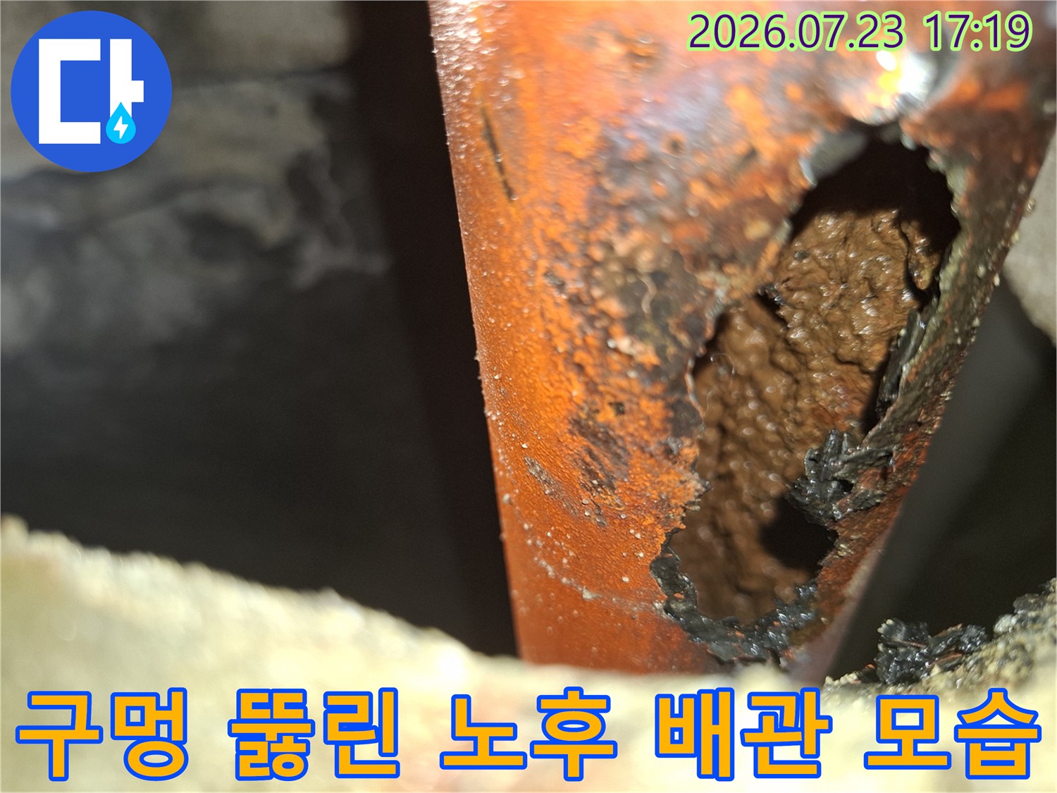 오렌지색 배관의 옆면이 부식되어 움푹 파이며 구멍이 형성된 누수 현장 사진