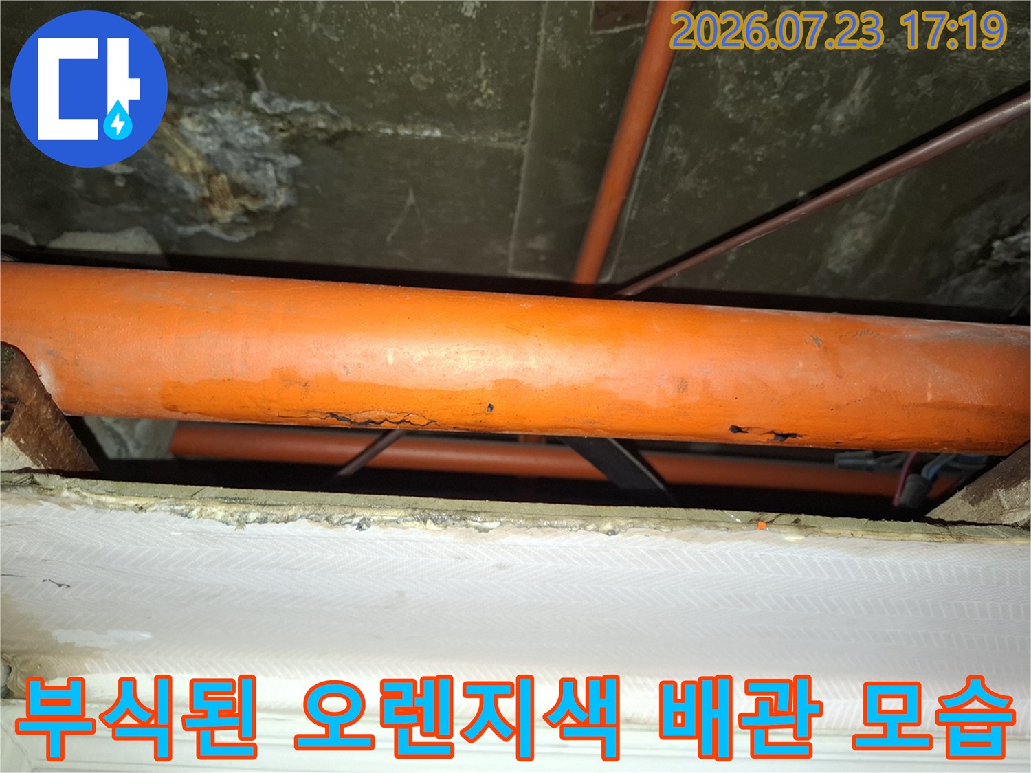 천장에 설치된 오렌지색 배관의 외벽이 부식되어 표면이 거칠어진 상태-누수 지점 확인 사진