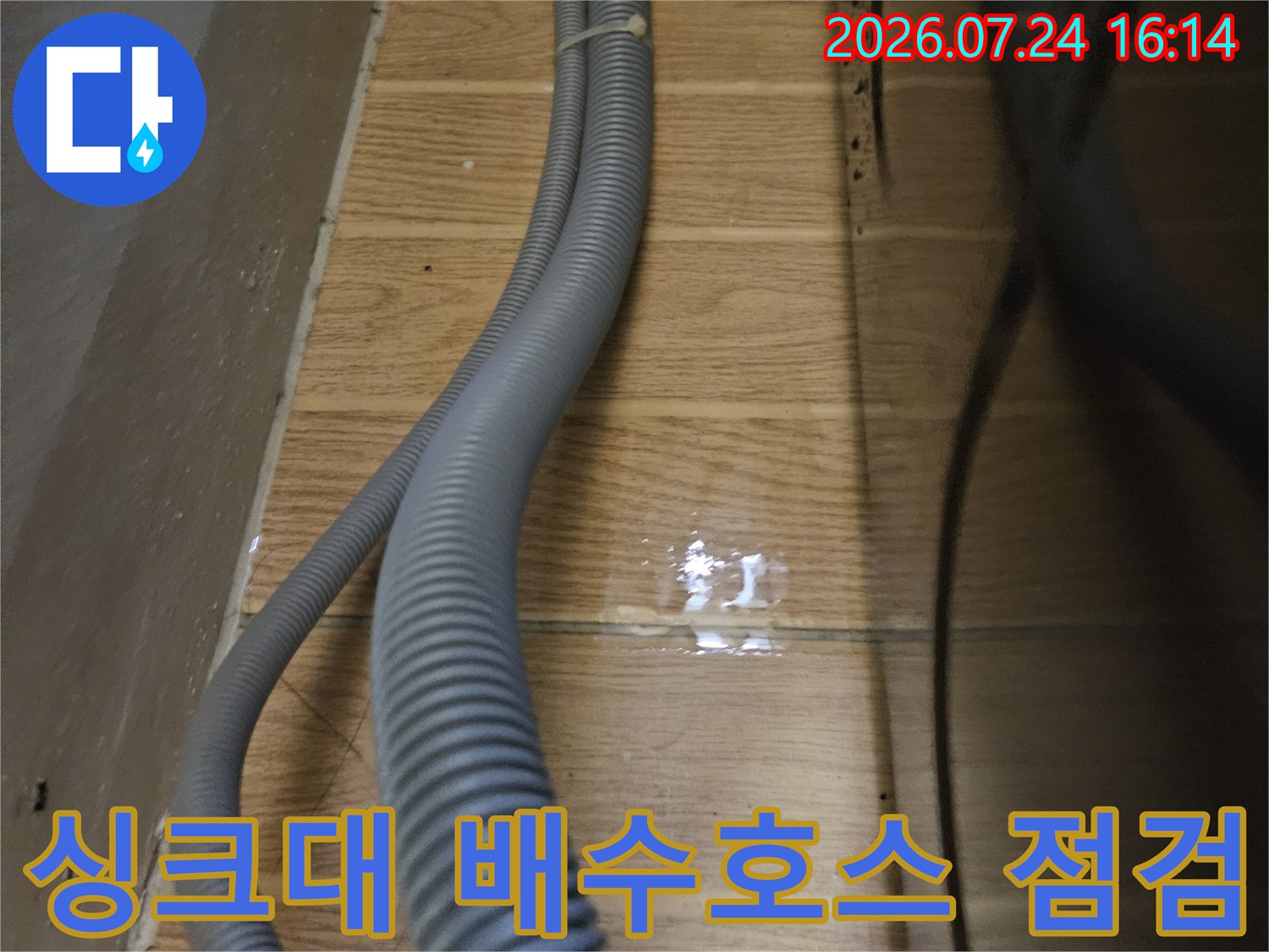 싱크대 아래 설치된 회색 배수 호스와 벽면 연결 부위의 상세 모습