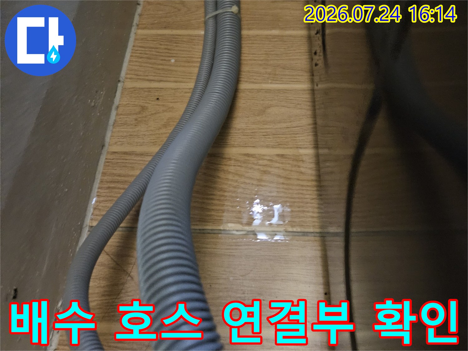 회색 주름 배수 호스가 벽면으로 이어지는 구간의 근접 촬영 사진