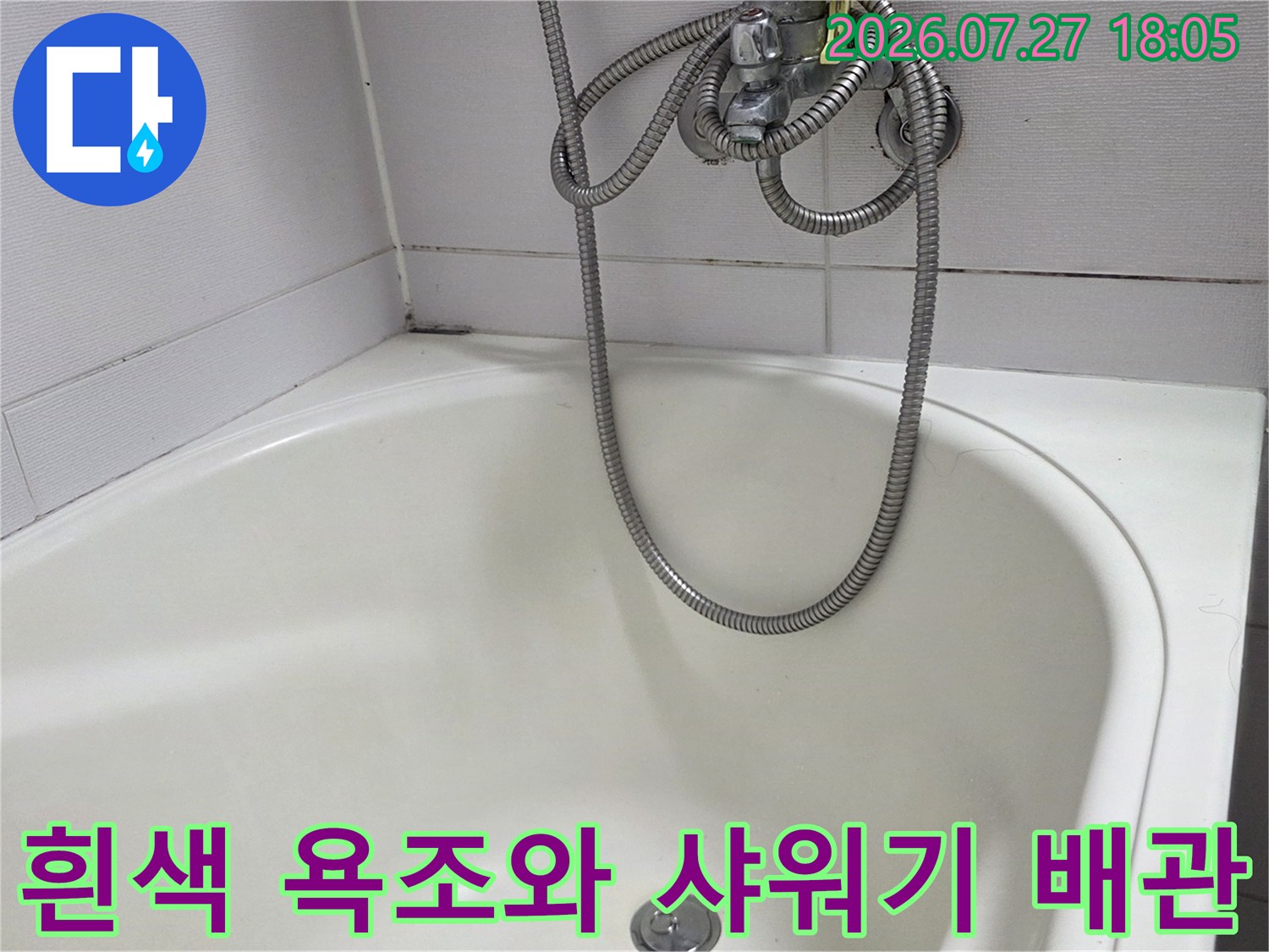 욕실의 흰색 욕조와 은색 메탈 소재의 샤워 호스가 배치된 모습