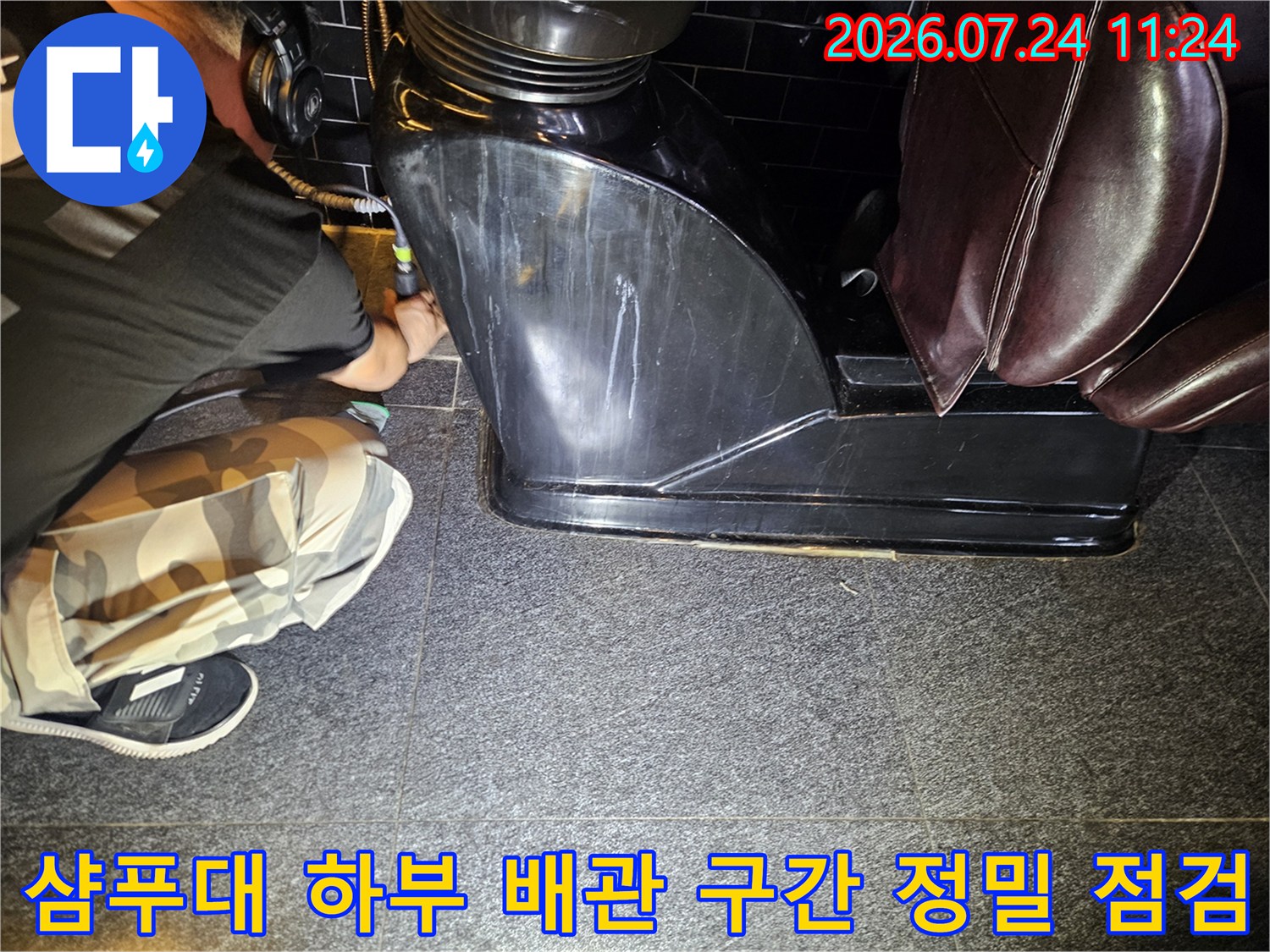 작업자가 샴푸대 아래쪽 바닥면과 연결된 배관 부위를 세밀하게 조사하는 장면