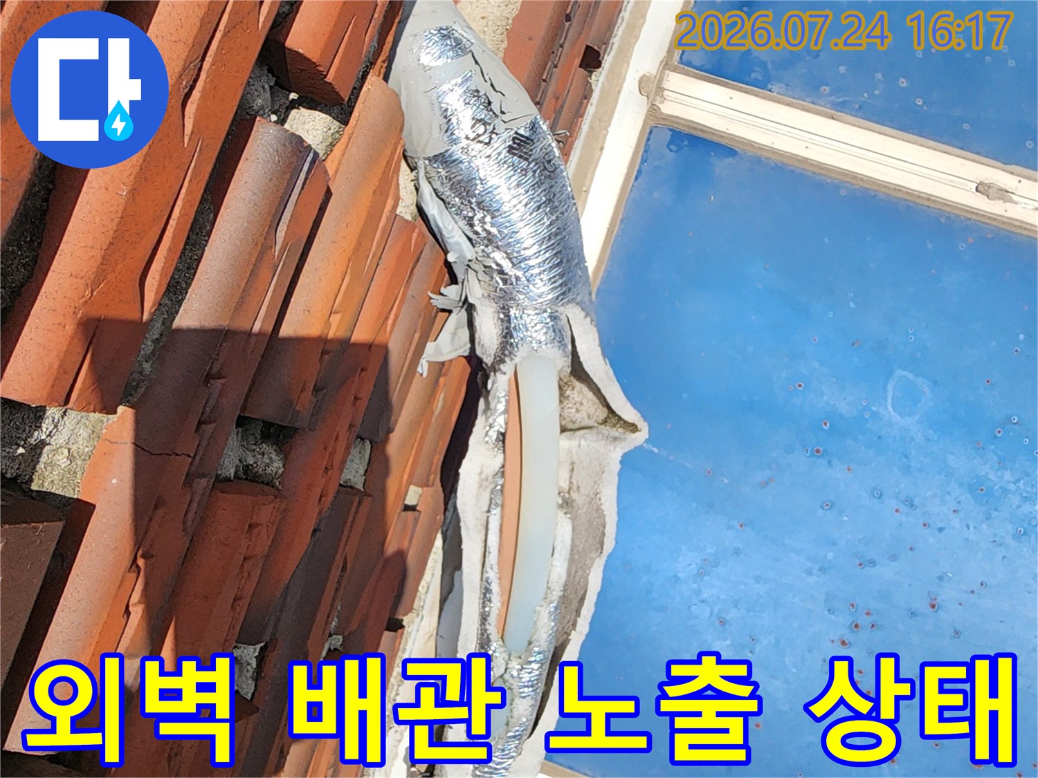 기와 지붕 위에 설치된 긴 은색 단열재 마감의 외곽 수도 배관 점검