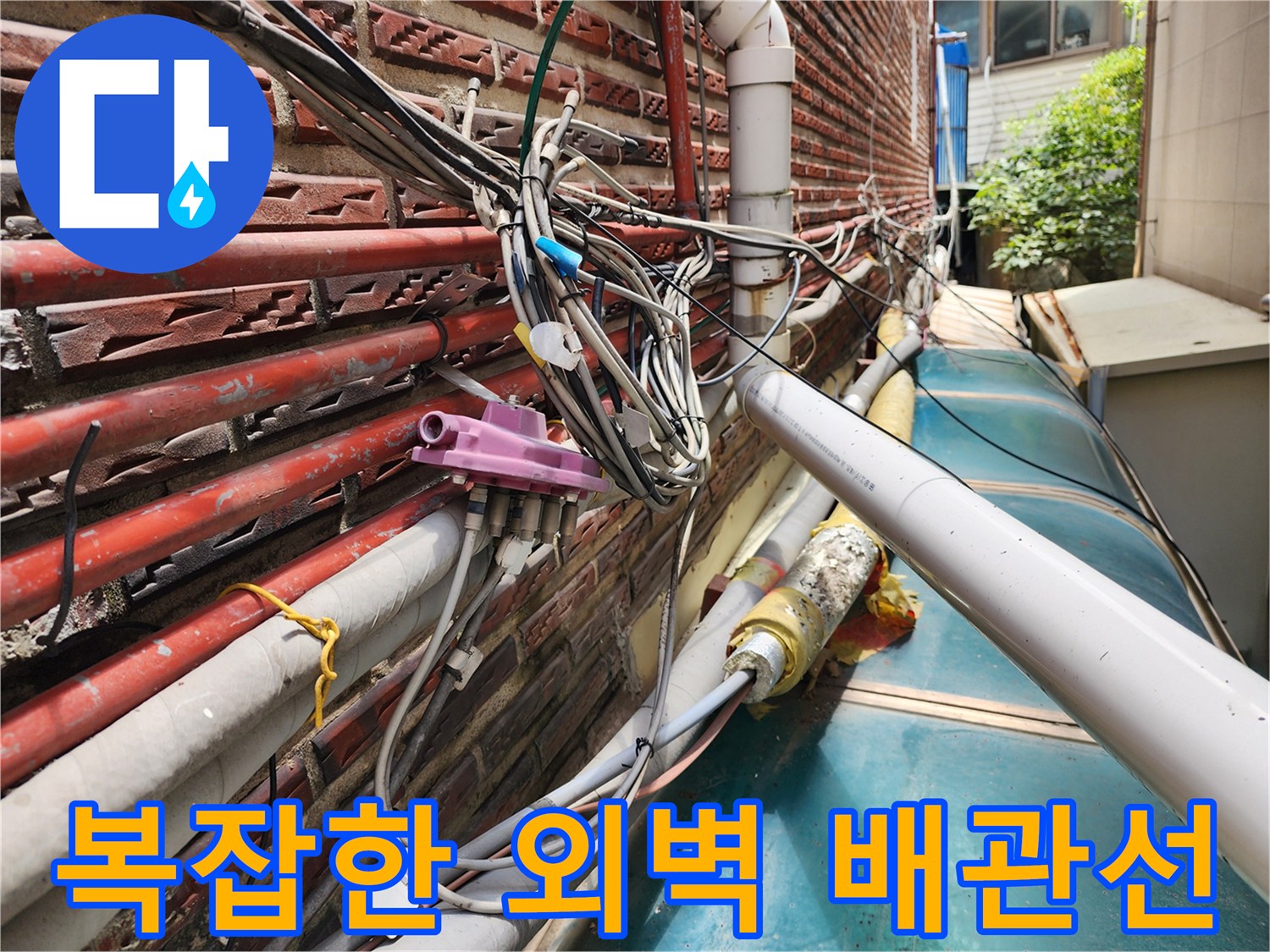 외벽 벽돌 사이로 연결된 여러 갈래의 수도 배관과 훼손된 보온재 상태