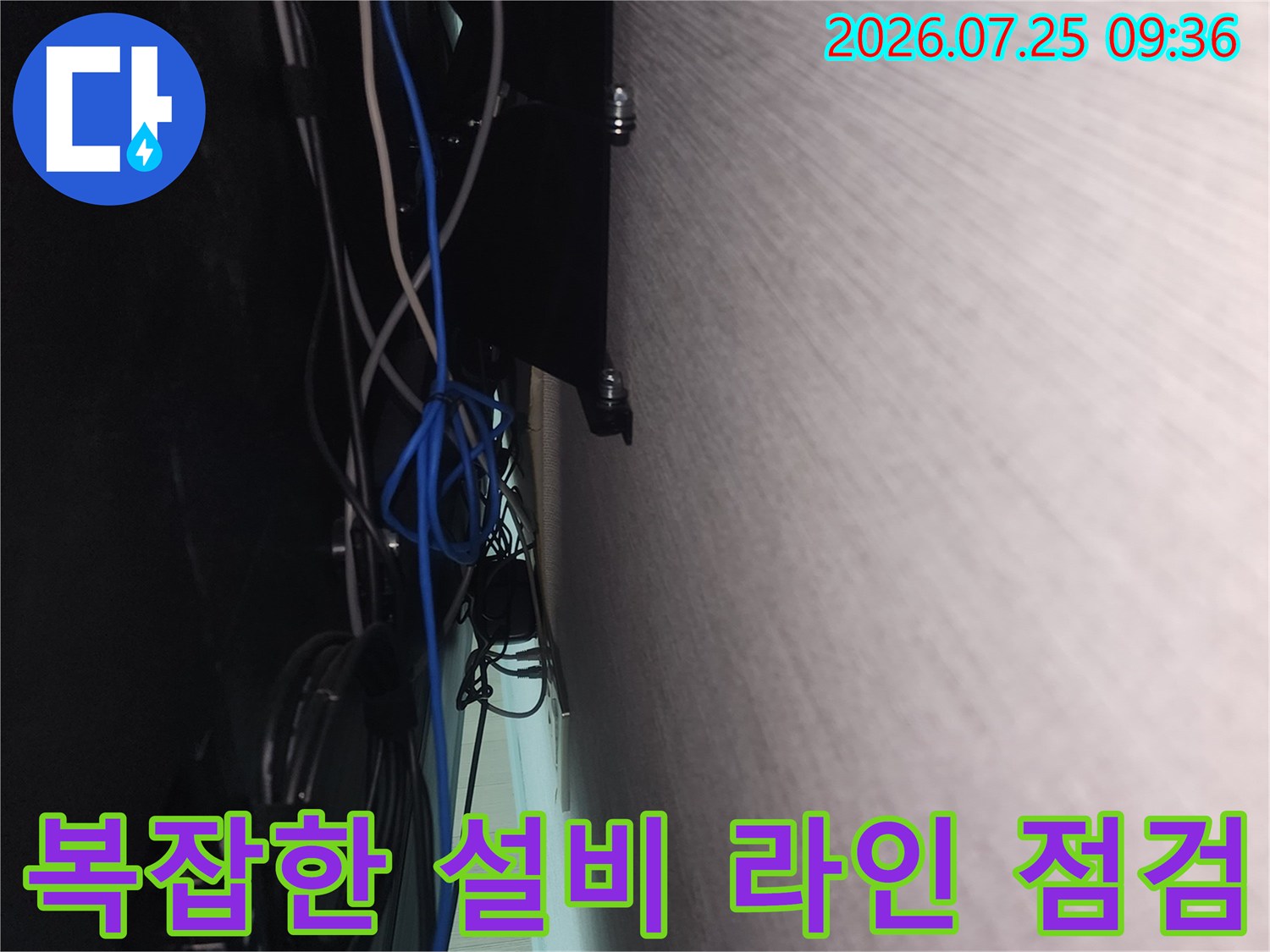 벽면을 따라 배치된 여러 가닥의 파란색 전선과 배관이 엉켜있는 구간을 촬영한 사진