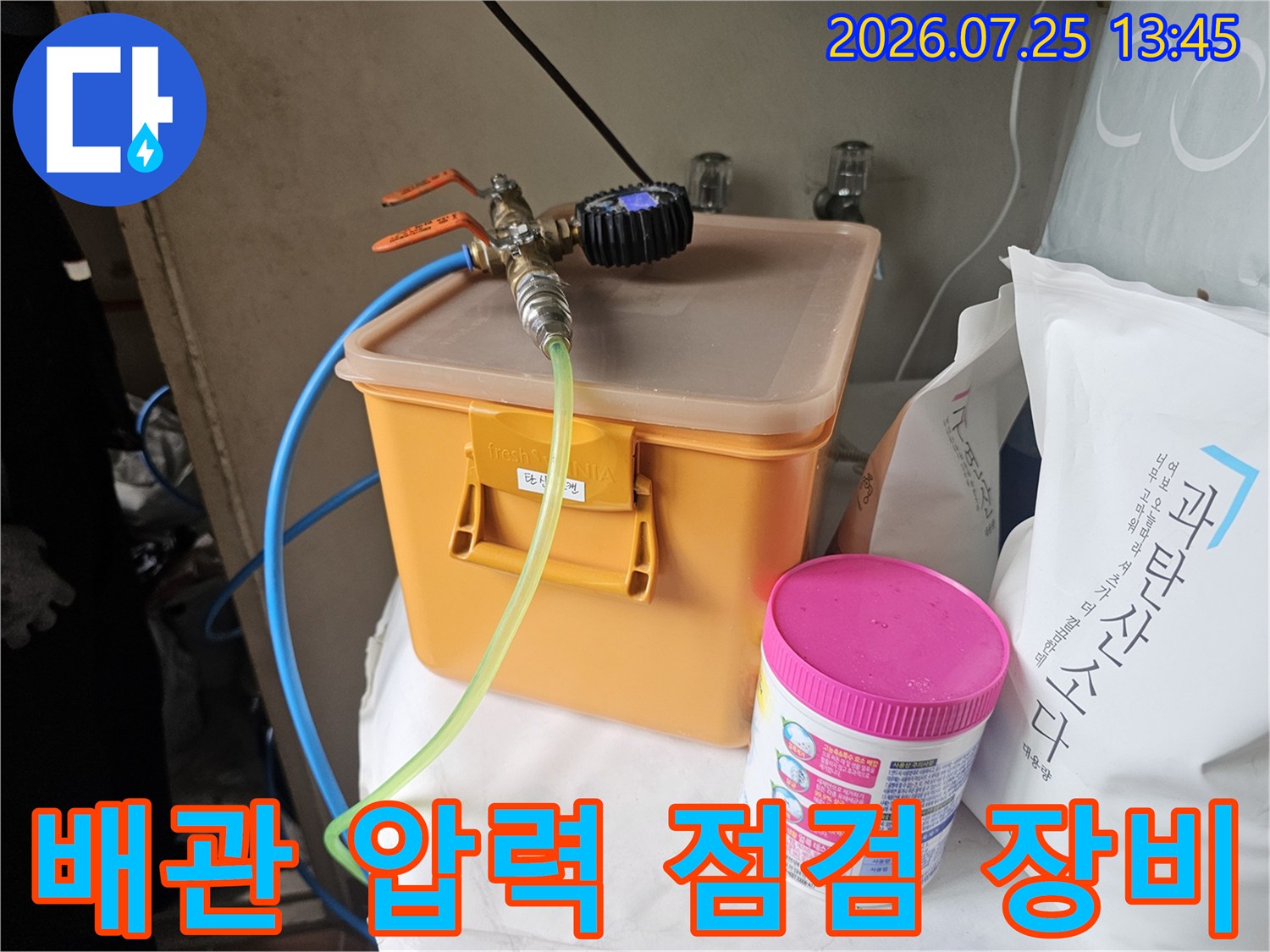 오렌지색 수납함 위에 설치된 배관 압력 테스트 장치와 게이지