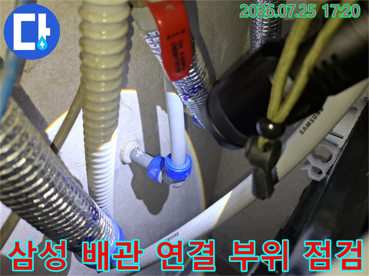 삼성 로고가 적힌 흰색 배관과 파란색 커넥터-빨간색 밸브 핸들이 보이는 누수 현장 사진