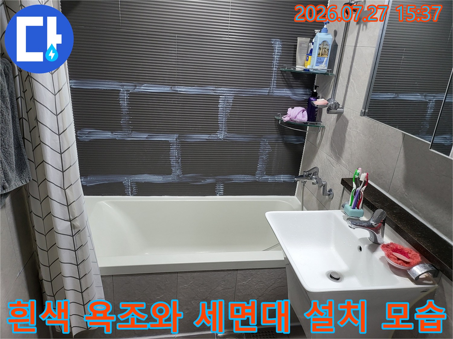 흰색 도기 재질의 세면대와 욕조-상단에 선반과 세면도구가 놓여 있는 화장실