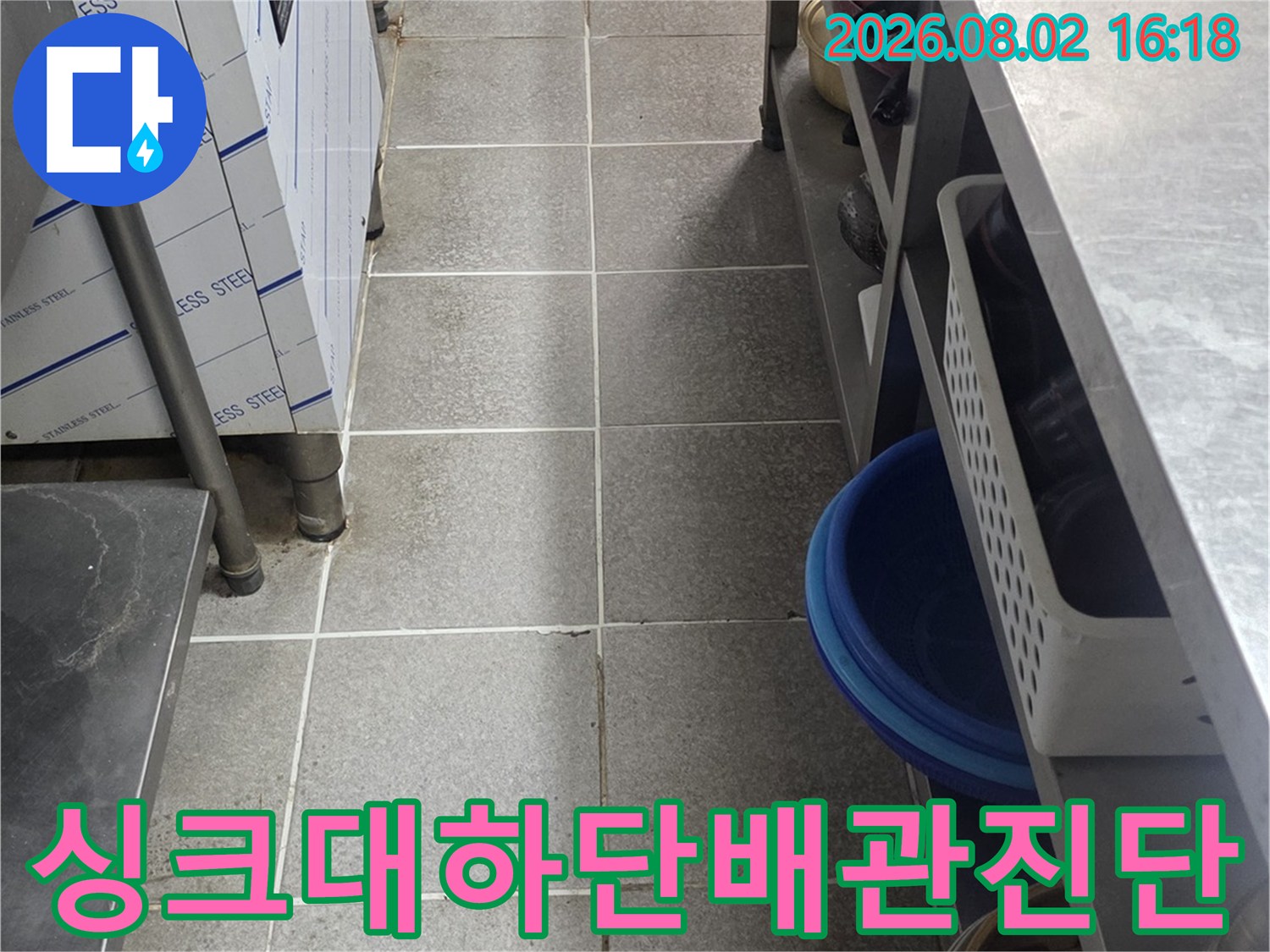 어두운 싱크대 아래 공간에서 배관 및 트레이 구조를 점검하는 모습