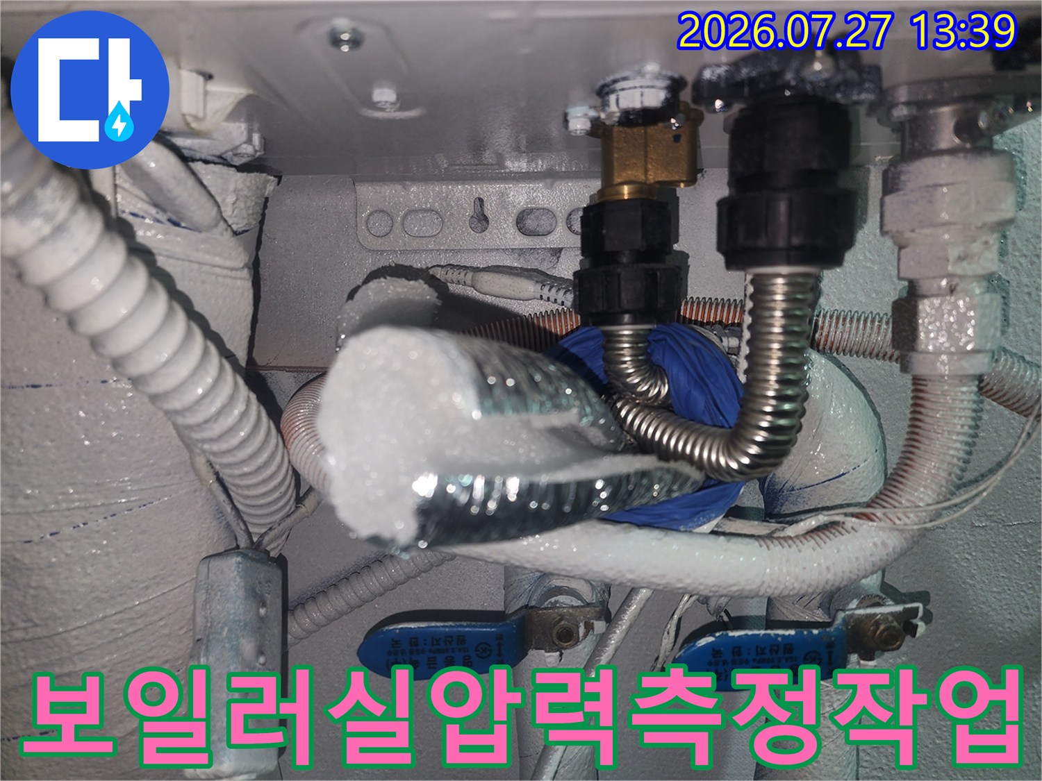 은색 보온재가 씌워진-보일러 배관에 공압 검사 장비를 연결해 측정하는 장면