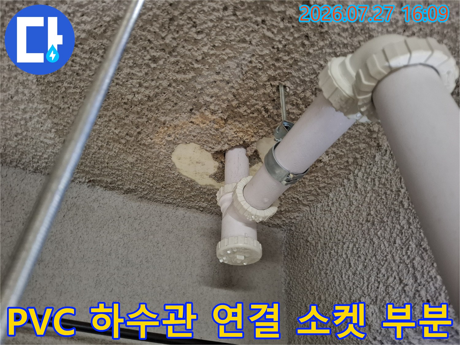 흰색 PVC 배관이 천장에 고정되어 있으며-연결 부위에 이물질과 습기가 보이는 사진