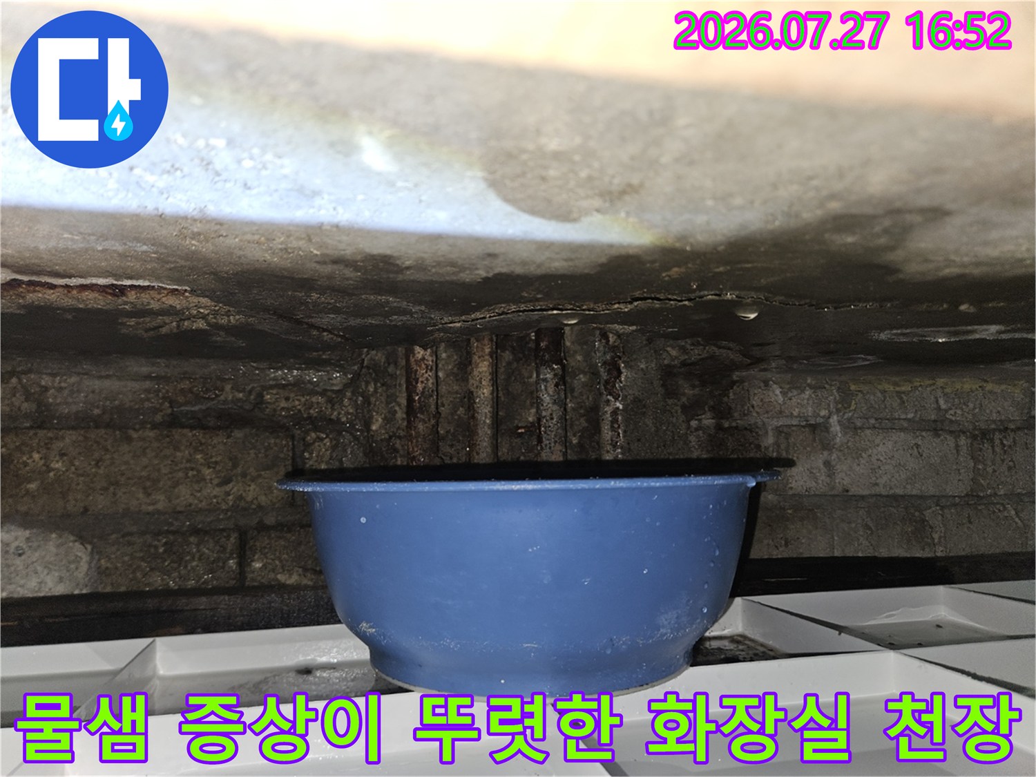 천장의 콘크리트 층에서 물이 새어 나와 아래에 파란색 대야가 놓여 있는 현장 사진