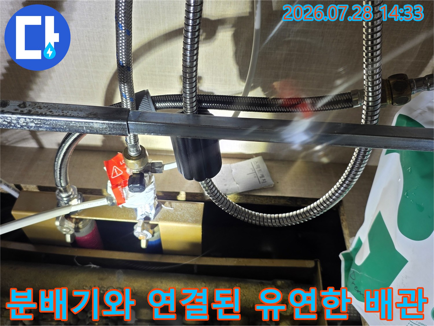 스테인리스 재질의 플렉시블 호스가 분배기 밸브에 체결되어 있는 모습-누수 점검 부위