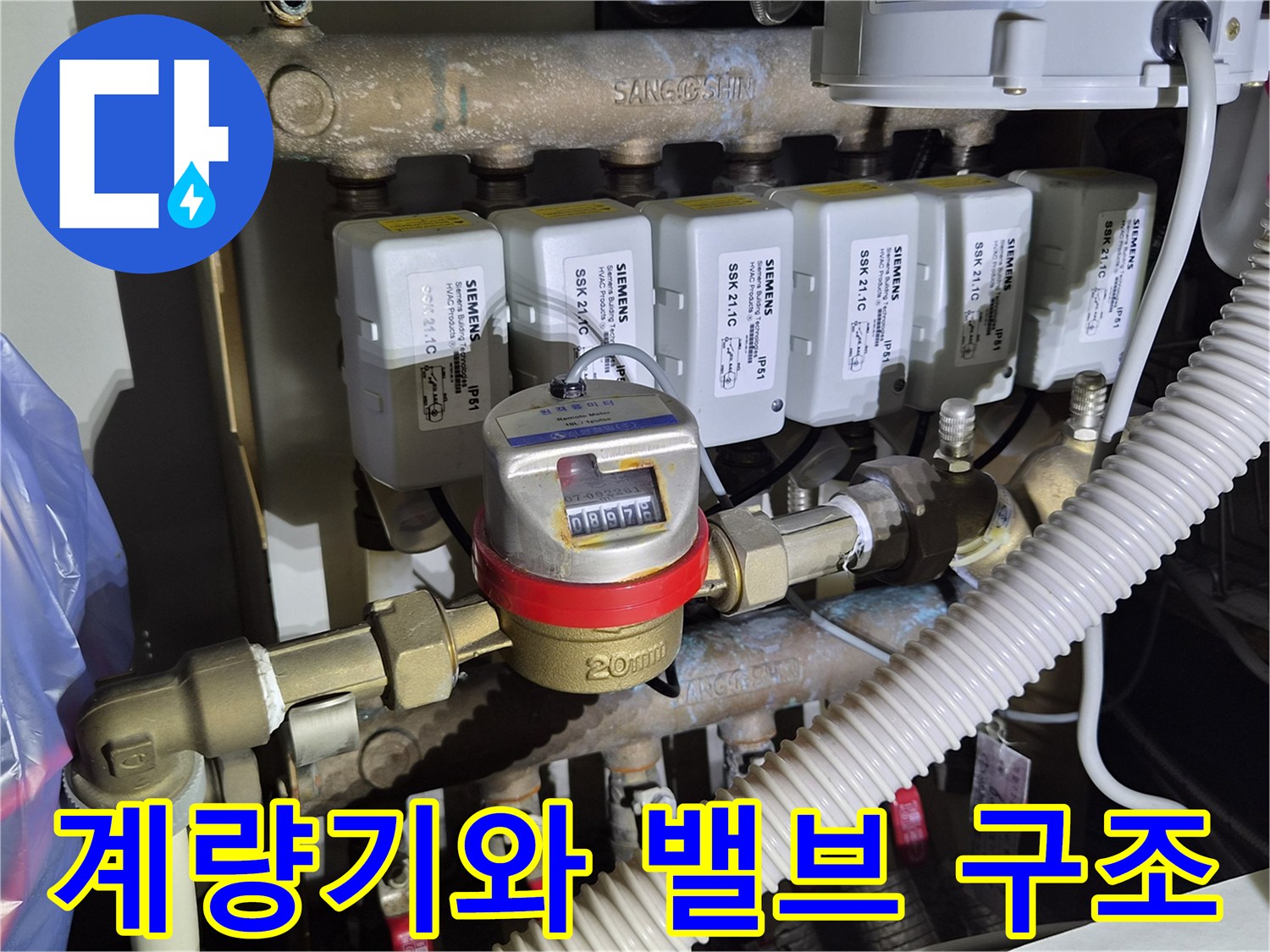 수도 계량기 수치와 분배기 밸브가 연결된 복잡한 배관 모습입니다.