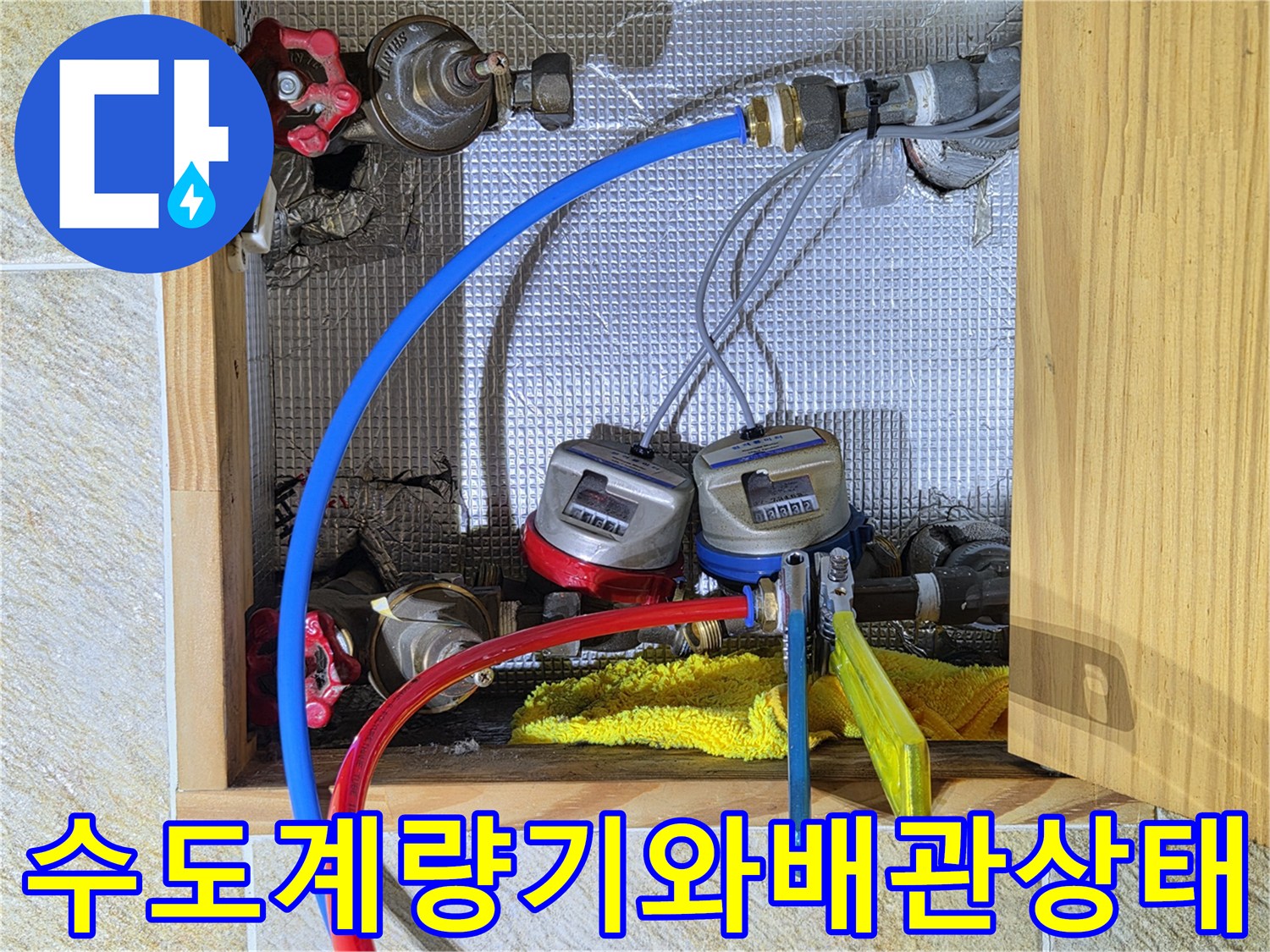 수도 계량기 주변의 파란색과 빨간색 배관 및 밸브 상태를 점검하는 모습