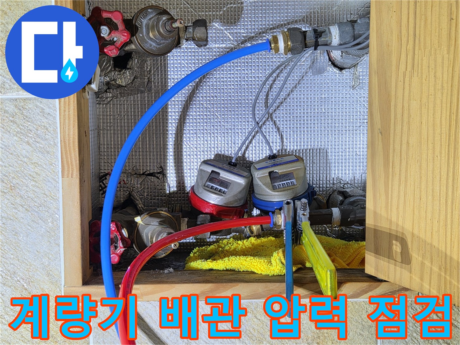 수도 계량기에 연결된 파란색 및 빨간색 배관의 근접 촬영