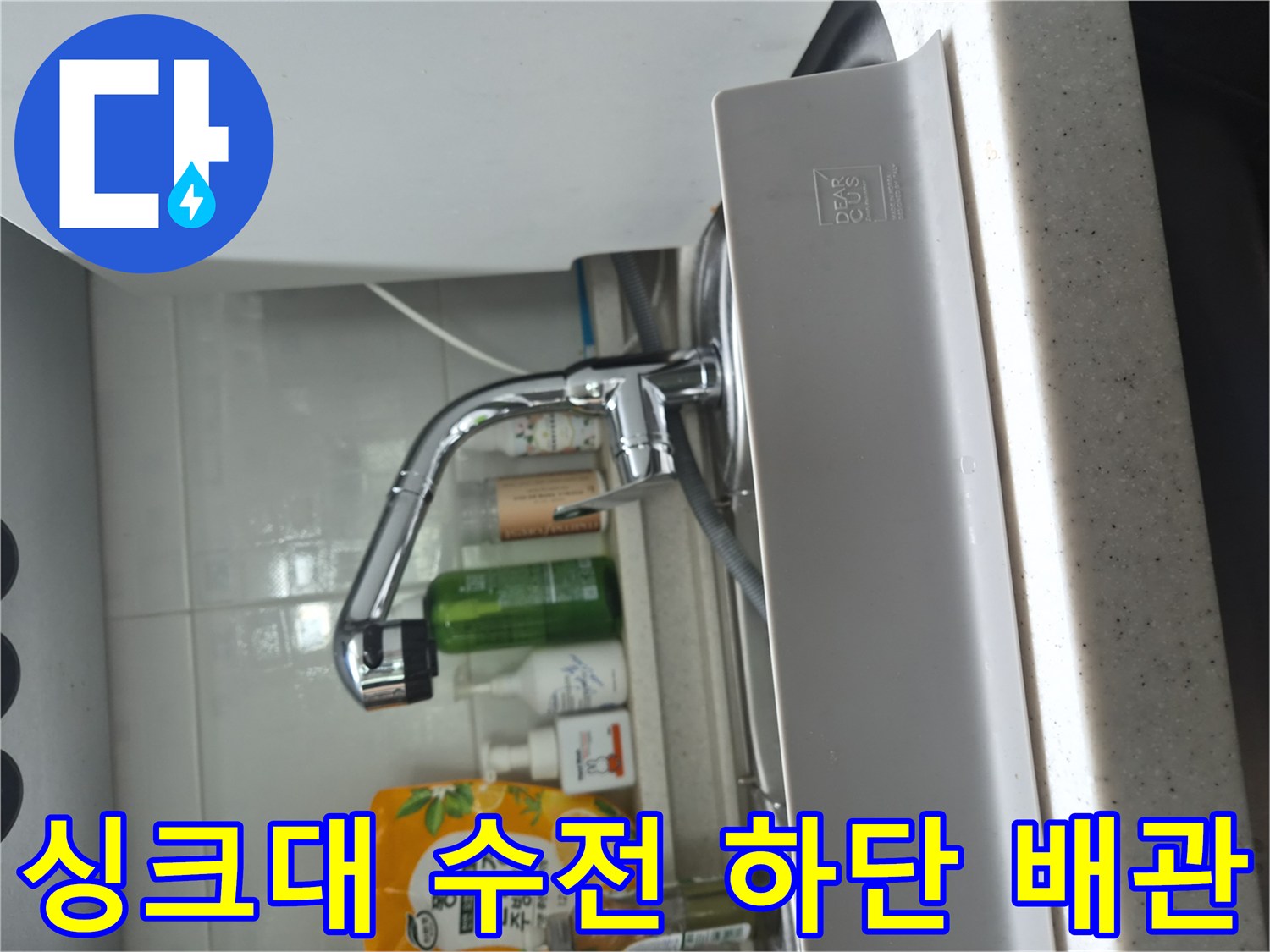 싱크대 하부장 내부에 설치된 은색 수전과 배관 라인