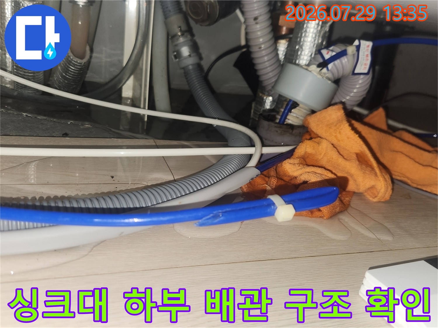 작업자의 장갑과 싱크대 아래 여러 가닥의 호스 및 배관 시스템