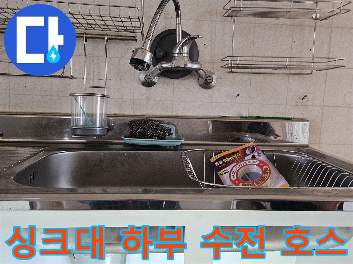 싱크대 아래쪽 수전 연결 호스와 주변 배관 부속의 근접 촬영 사진입니다.