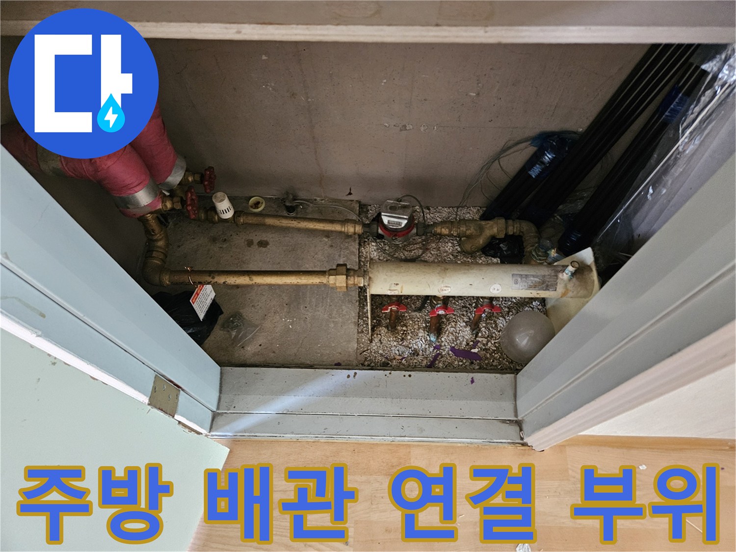 싱크대 하부장의 금속 배관과 붉은색 보온재 처리된 분기 배관