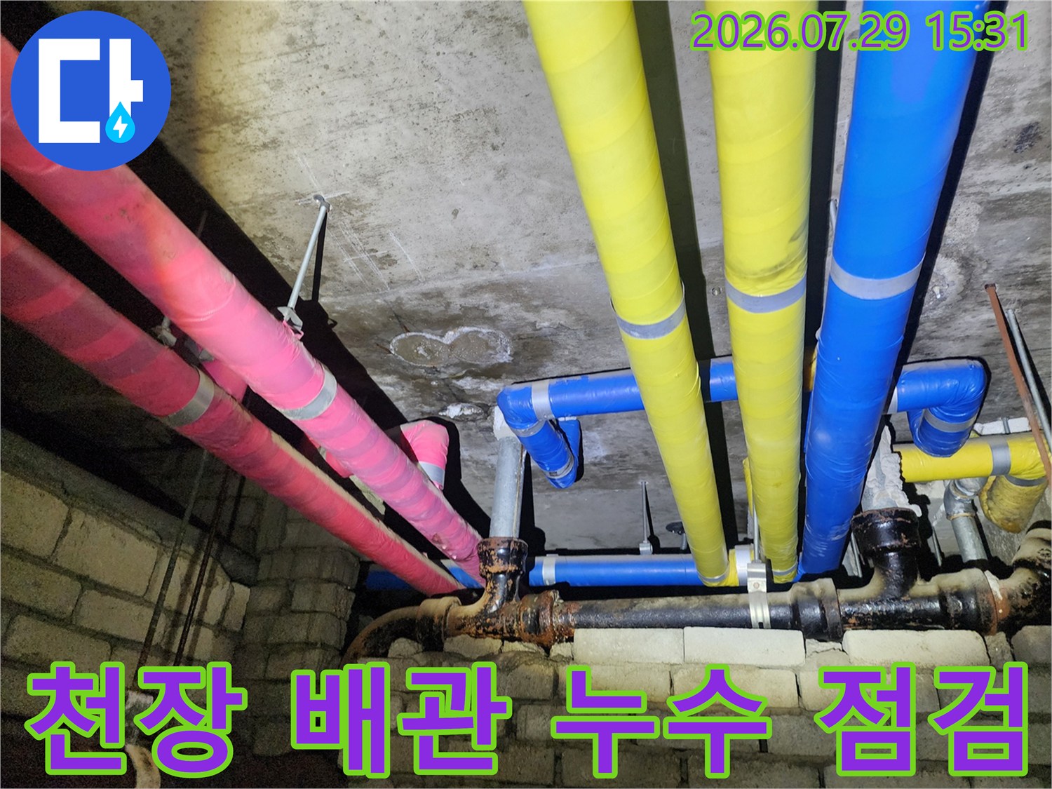분홍색과 노란색 보온재로 감싸인 천장 배관 라인 점검 모습