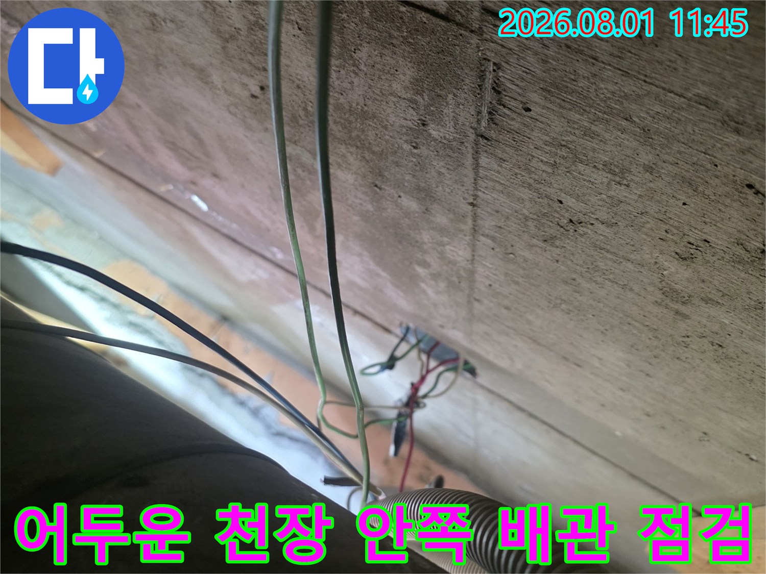 어두운 공간에서 노출된 배선과 배관을 확인하며 누수 경로를 파악하는 모습
