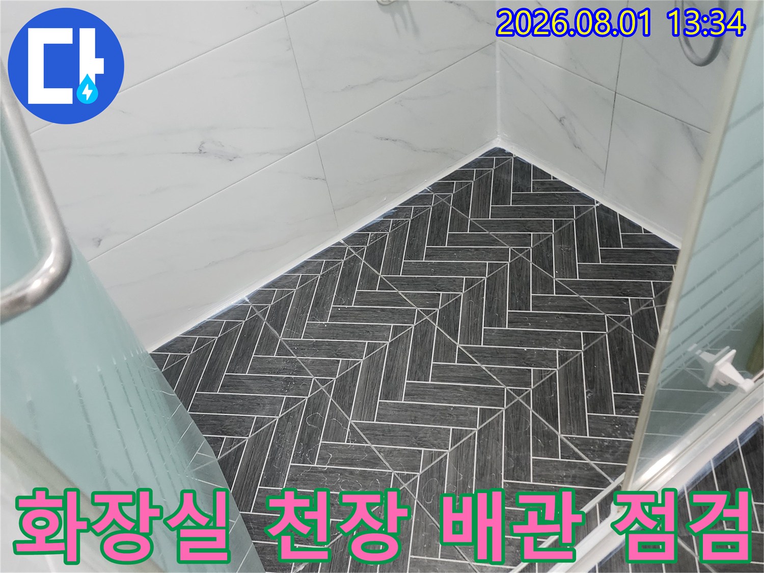 화장실 천장 내부의 노출된 배관과 타일 마감면 점검 모습