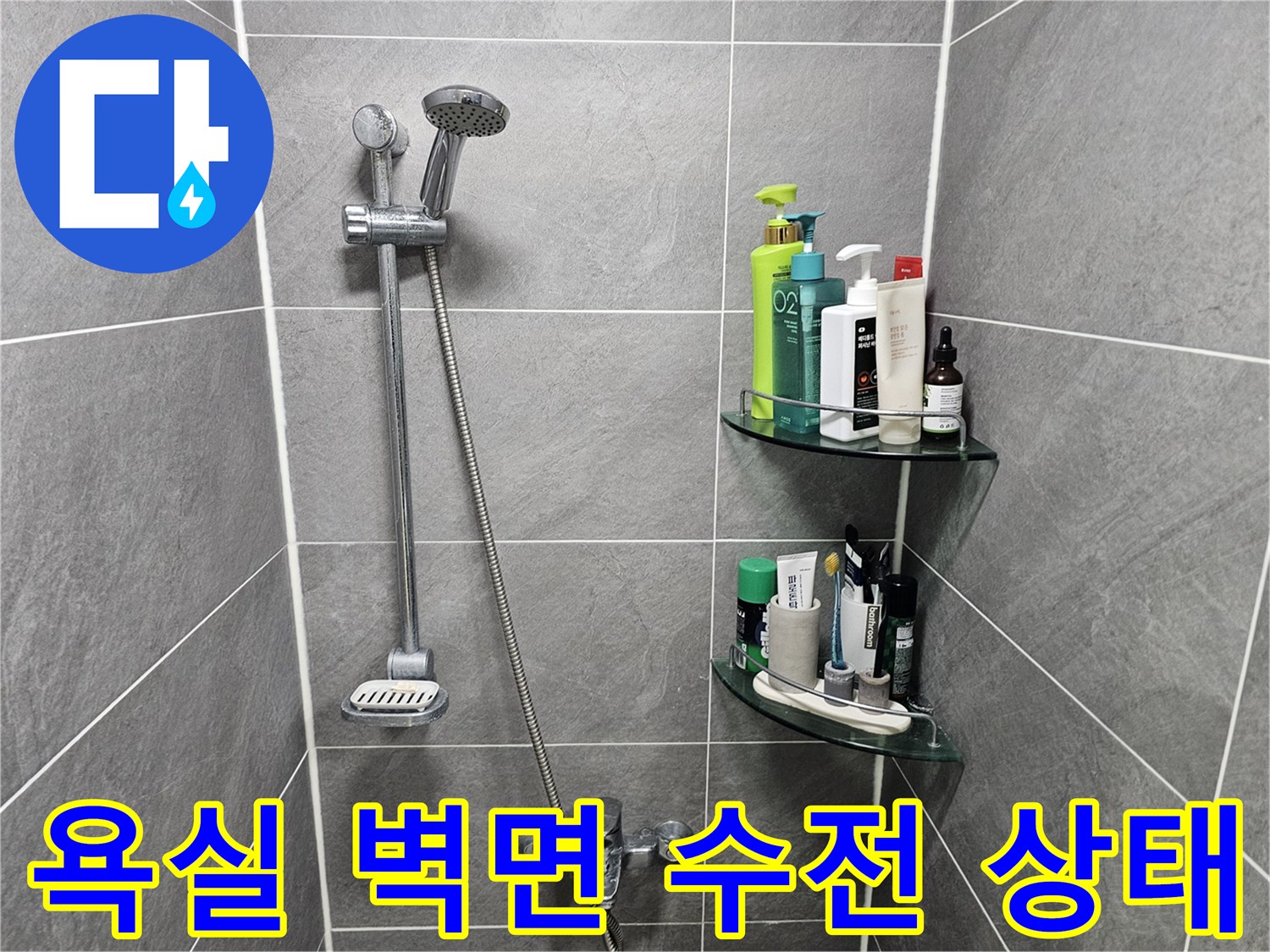 샤워기 헤드와 수전이 설치된 회색 타일 벽면 모습
