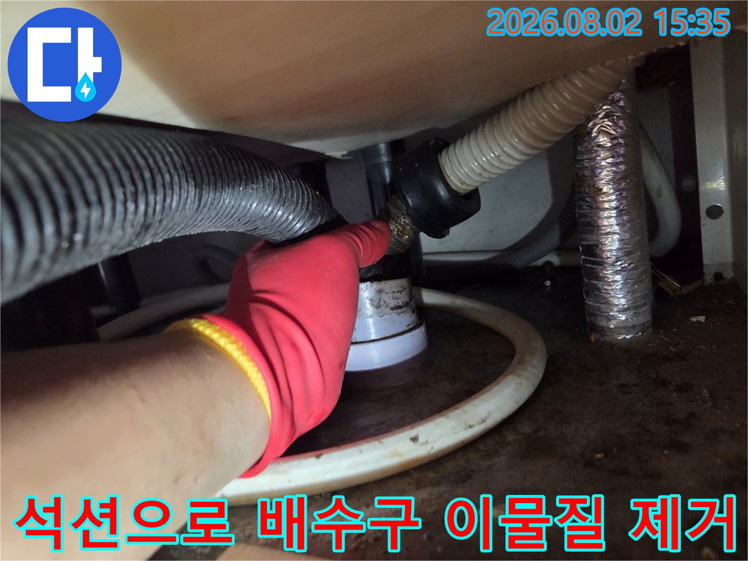 싱크대 하단부의 복잡한 배관 구조에서 석션 호스를 연결해 내부 찌꺼기를 뽑아내는 모습