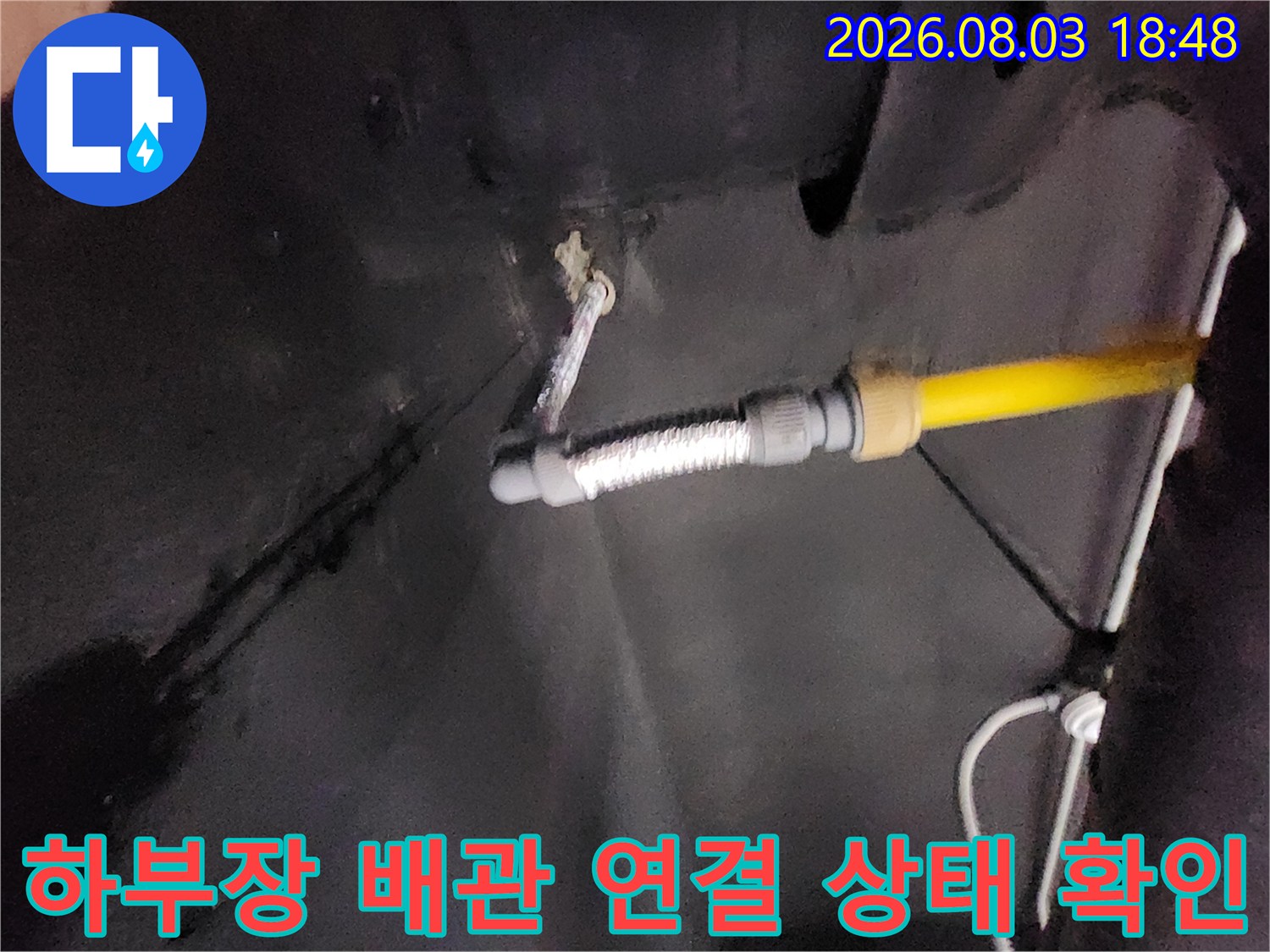 싱크대 하단부에 노출된 노란색 보호 배관과 금속 주름 호스 구성
