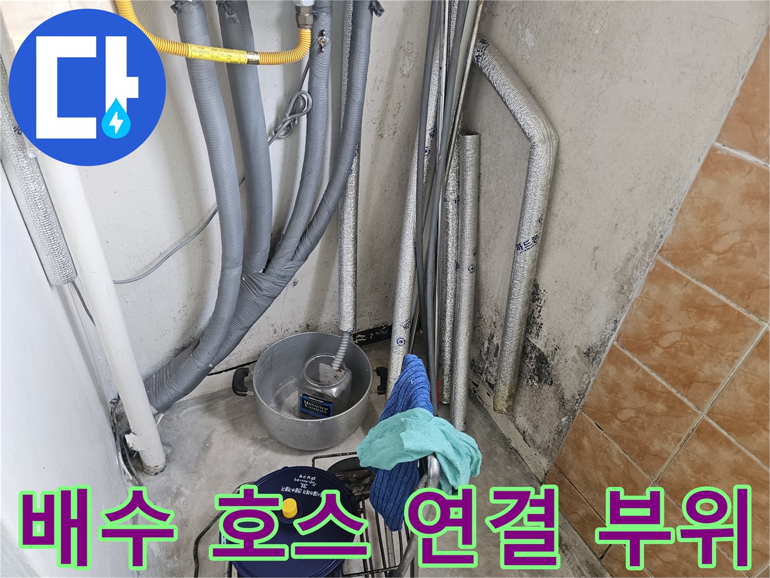 세탁실 내부-회색 주름관과 배수용 호스가 모여 있는 배관 구조