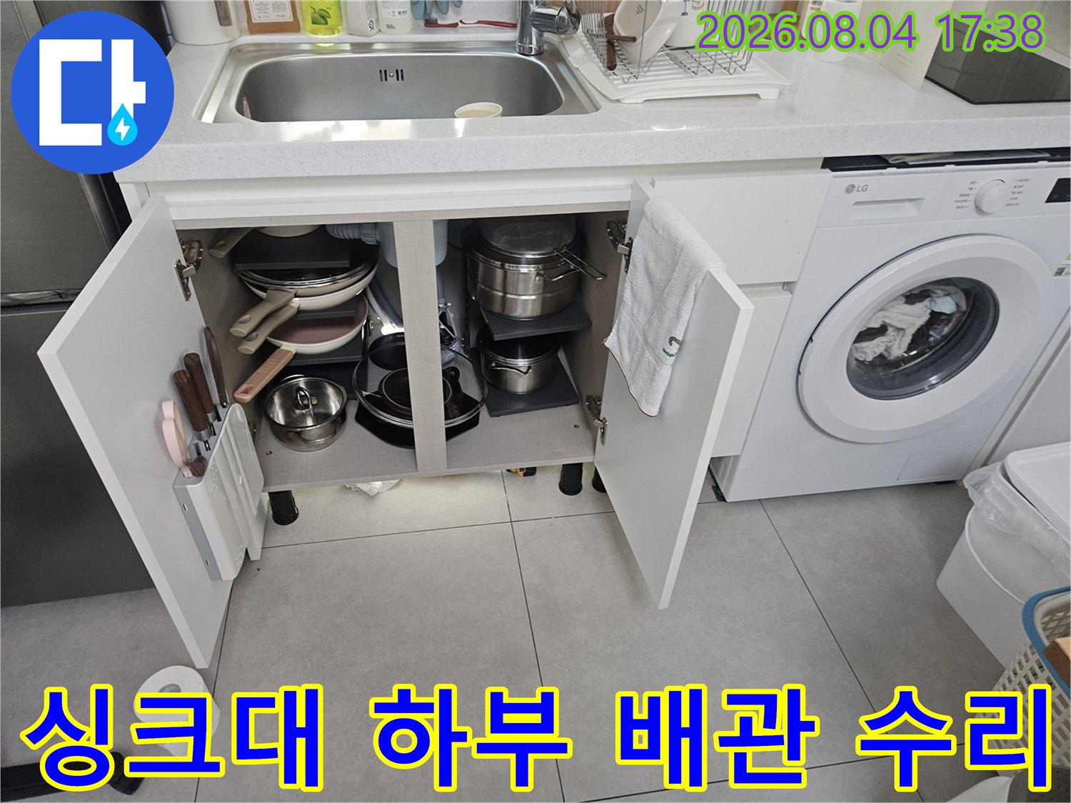싱크대 하부장에서 노출된 수도 및 온수 배관을 점검하는 실무 현장 사진