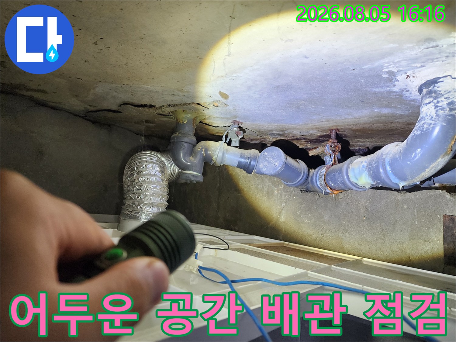 손전등으로 조명한 화장실 천장의 노출 파이프라인과 연결부위