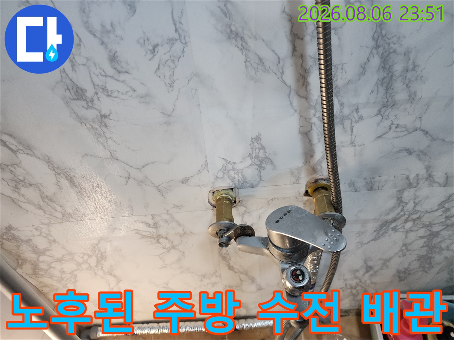 벽면에 설치된 금속 재질의 수전과 연결 호스 상세 모습