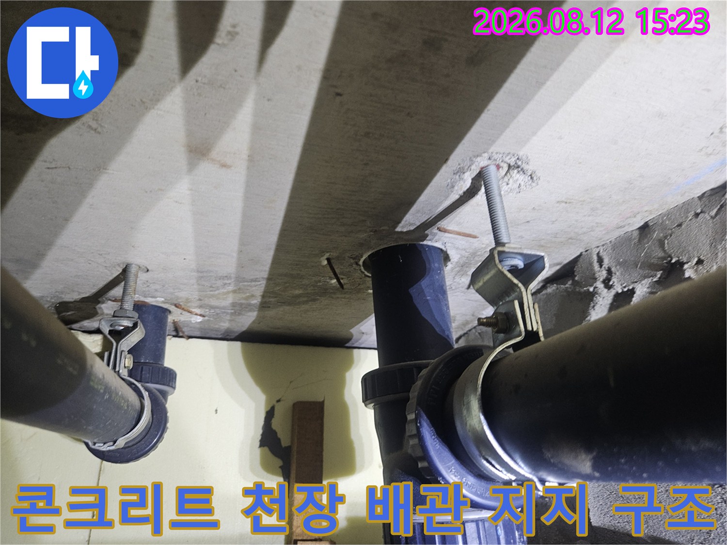 금속 행거와 볼트로 고정된 천장 하수 배관의 세부 모습