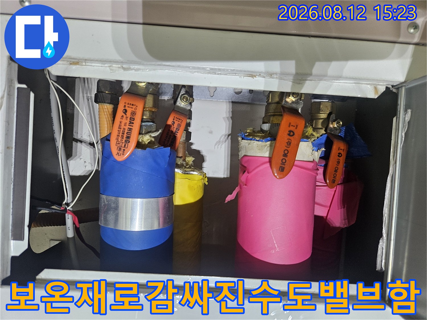 다양한-색상의-보온재가-시공된-배관과-주황색-손잡이-밸브의-근접-사진