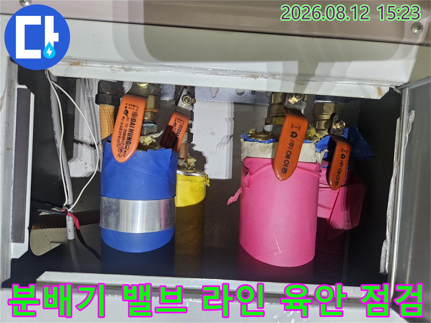보온재로 감싸진 배관들과 주황색 조절 밸브가 설치된 모습