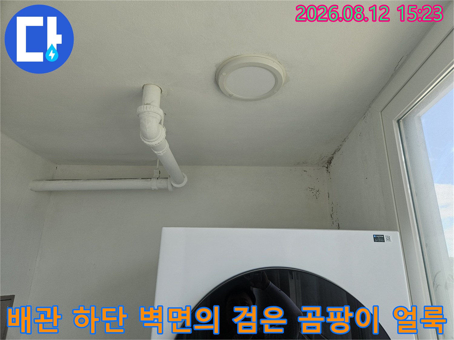 천장의 흰색 배관과 그 옆 벽면에 나타난 세로 방향의 검은 곰팡이 자국-누수 증거