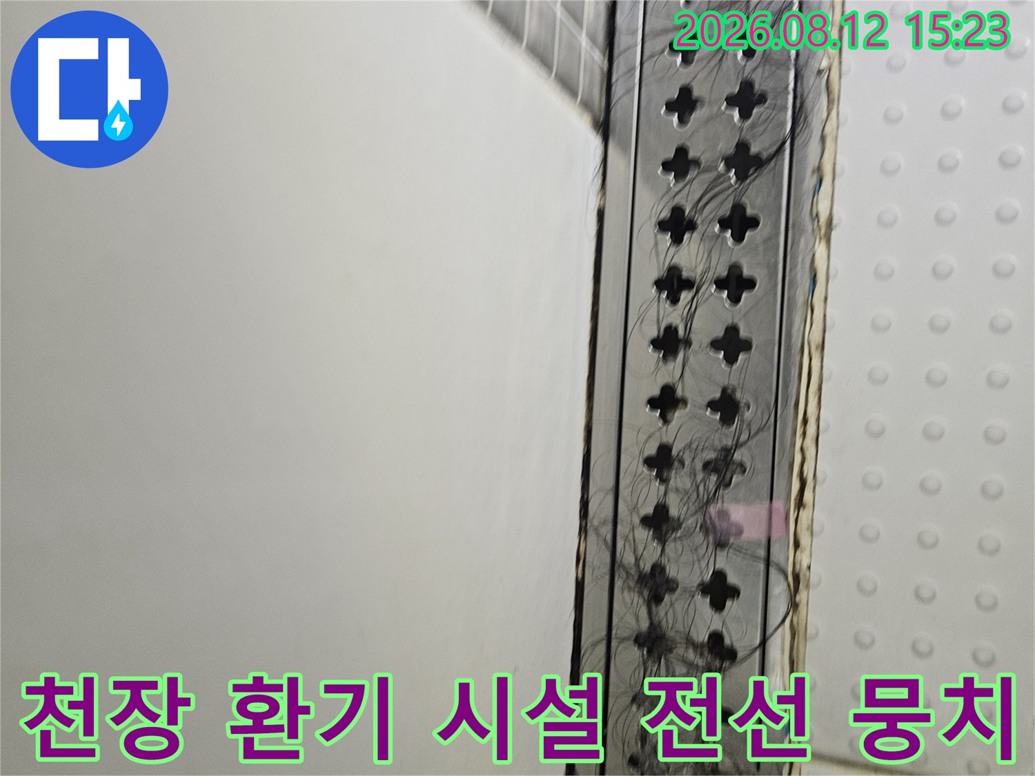 흰색 천장 배경에 설치된 검은색 환기 그릴과 복잡한 내부 배선들