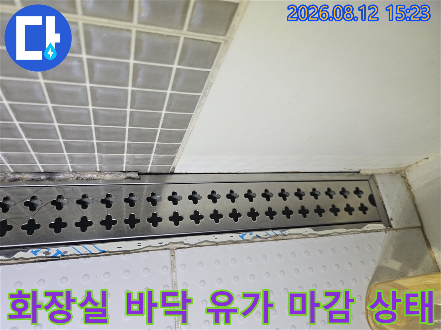흰색-타일과-접한-스테인리스-재질의-긴-배수구-덮개